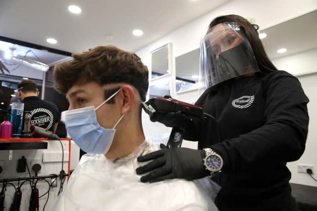 Barber Margaret McGillivray with customer Mitchell Wildman in the chair at Tony Mann's Barber Shop in  Glasgow, which opened at midnight as lockdown restrictions are relaxed