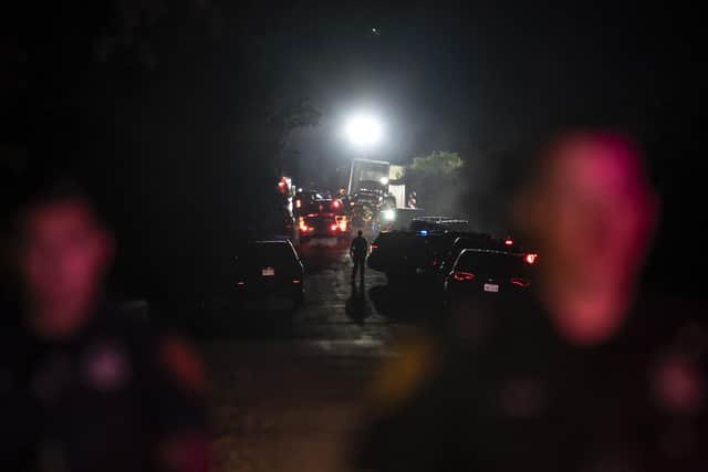 TOPSHOT - A first responder walks through the scene where a tractor-trailer was discovered with migrants inside outside San Antonio, Texas on June 27, 2022. - At least 46 migrants were found dead June 27, 2022 in and around a tractor-trailer that was abandoned on the roadside on the outskirts of the Texas city of San Antonio. (Photo by Sergio FLORES / AFP) (Photo by SERGIO FLORES/AFP via Getty Images)