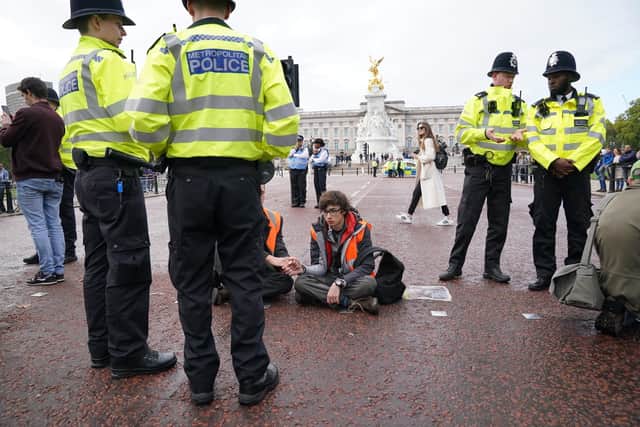 Police officers stand by campaigners from a Just Stop Oil protest as they sit on The Mall, near Buckingham Palace, London.