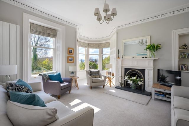 Drawing room with open fire and large sash and case windows, including a pretty turret.