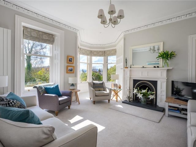 Drawing room with open fire and large sash and case windows, including a pretty turret.