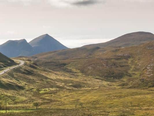 The A835 road winding past Knockan Crag with Cul Beag mountain in the background.