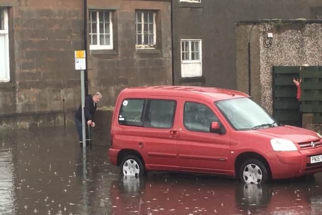 A man measures the depth of flood water on Kirkcaldys promenade.