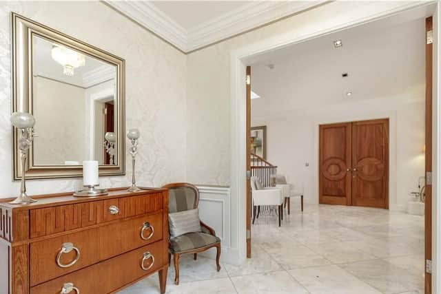 The entrance hall has marble flooring and large wooden doors.