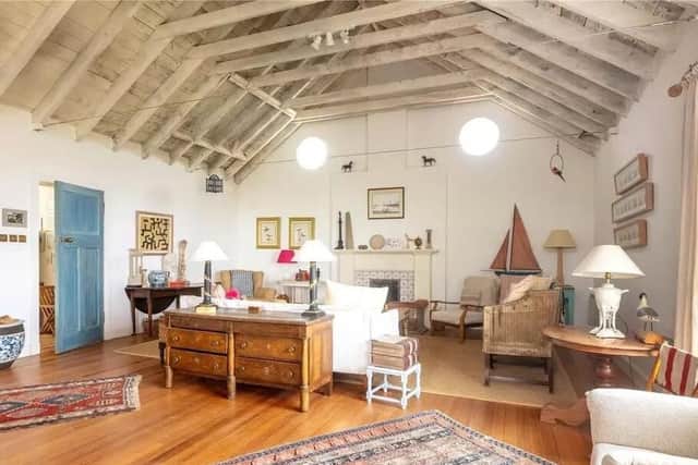 The open plan living room has exposed timber beams and a feature fireplace.