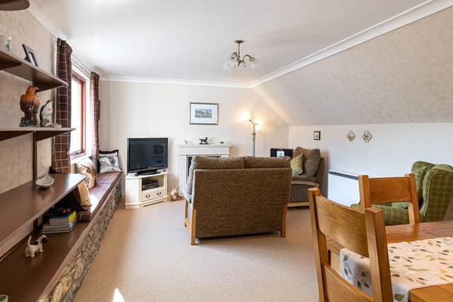 The living room features original exposed stone work and has space for a dining area.