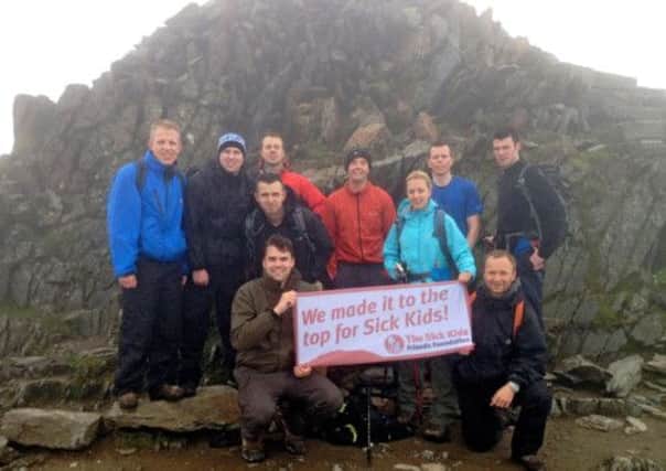 The Lloyds team unfurls the SKFF banner at the top of Snowdon