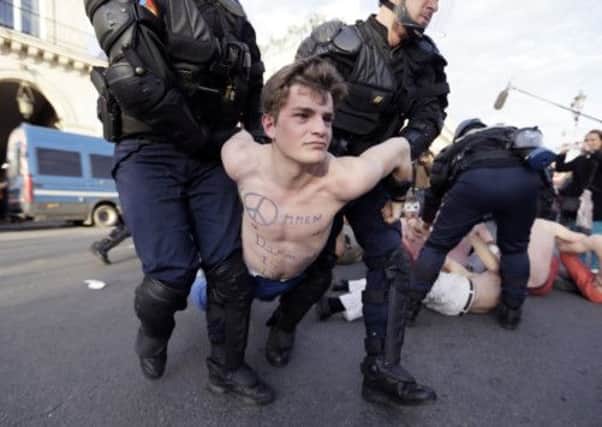 A bare chested man belonging to the anti-gay marriage group, Hommen, is detained by Parisian riot police. Picture: AFP/Getty