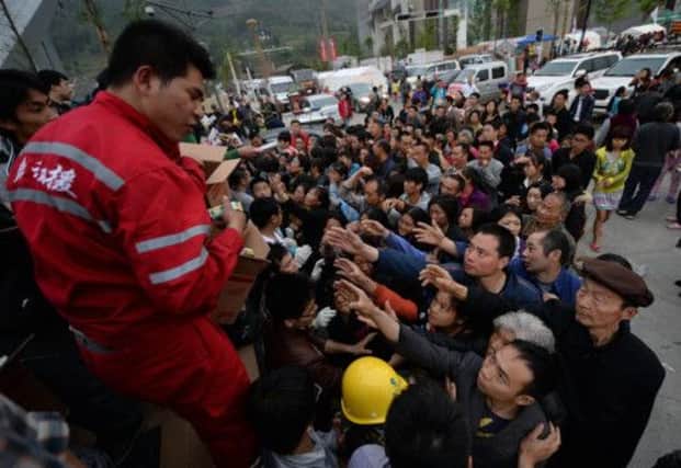 Willing hands pull a woman from the rubble in Baosheng Township, and hands reach out for relief supplies of food. Picture: Getty