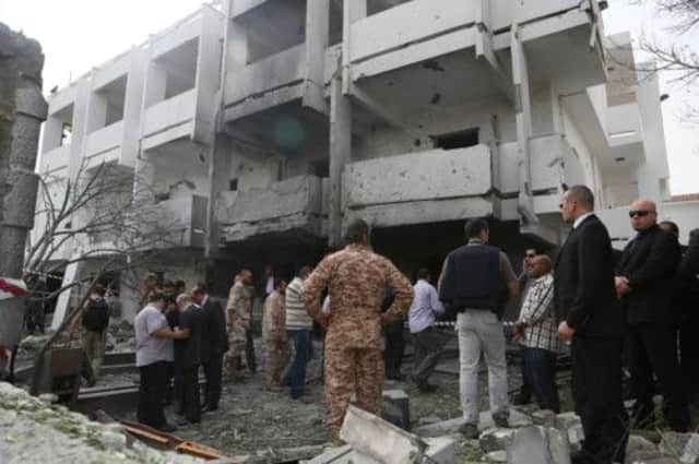 Security officers and officials inspect the site of a car bomb that targeted the French embassy in Tripoli. Picture: AP