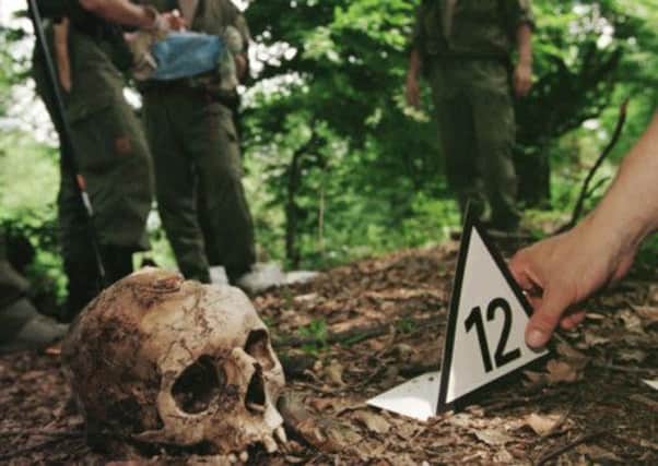 A forensic expert puts a number next to the excavated skull of a Srebrenica victim. Picture: AP