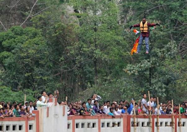 Sailendra Nath Roy is watched by onlookers as he hangs on a rope while attempting to cross the River Teesta. Picture: Getty