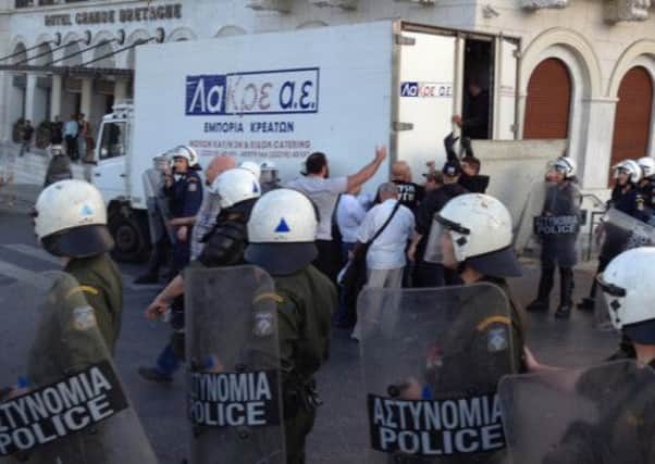 Members of Golden Dawn try to organize a 'Greek-only' food service as riot police look on. Picture: AP