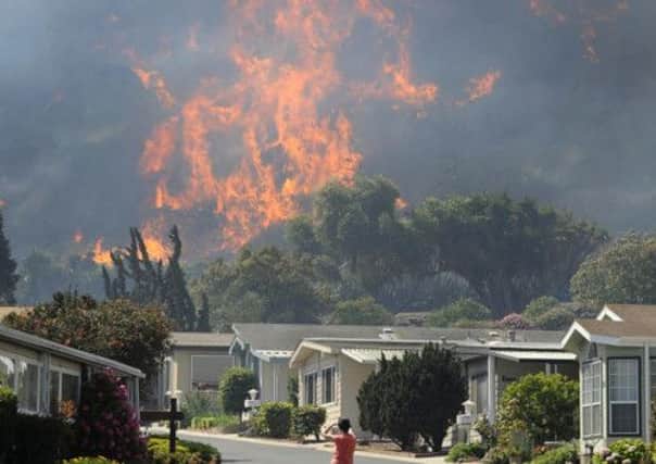 A resident watches flames race across hills as a raging brush fire pushes towards the coast in Camarillo. Picture: Reuters