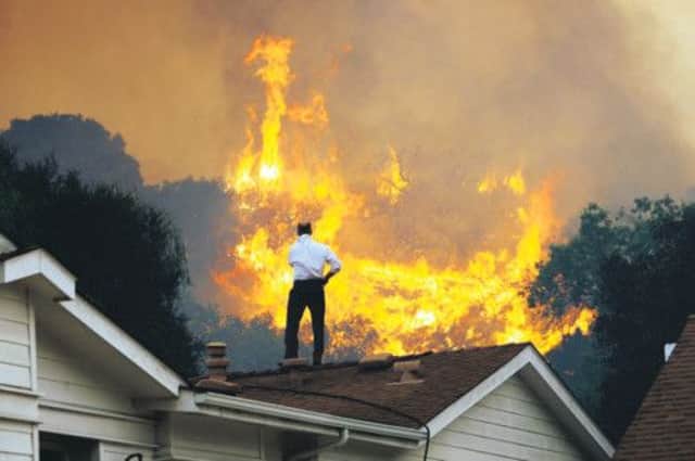 A man on a rooftop looks at approaching flames as the Springs fire continues to grow. Picture: Getty