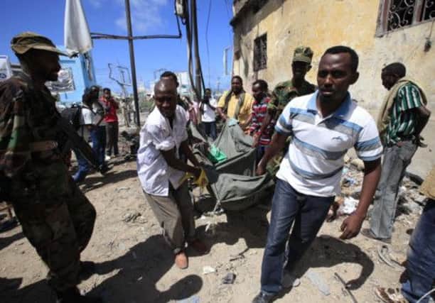 A casualty is removed from the scene of carnage after a car bomb exploded in the centre of Mogadishu yesterday. Picture: Reuters