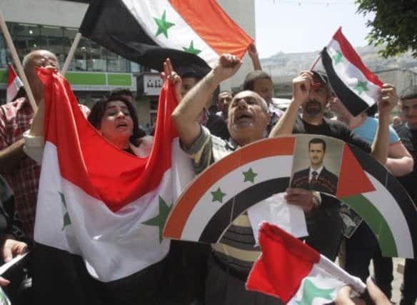Palestinians hold Syrian flags during a march in solidarity with the regime yesterday. Picture: AP