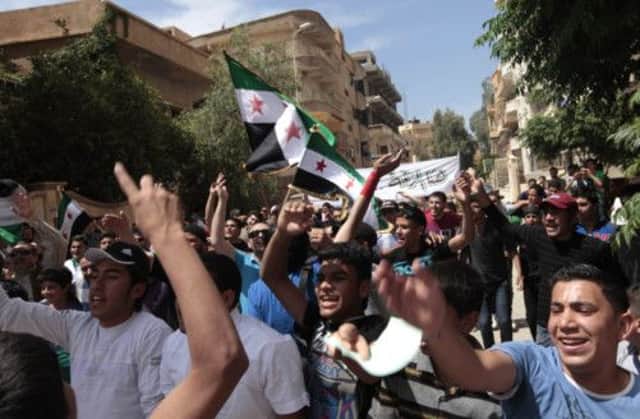 Demonstrators against president Bashar al-Assad wave Syrian flags after Friday prayers in rebel-controlled Raqqa. Picture: Reuters