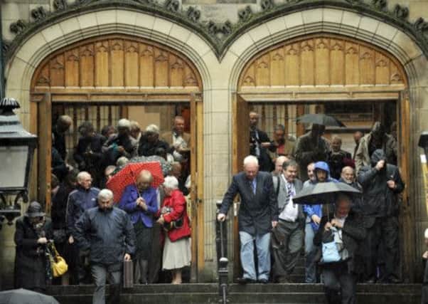 Commissioners leave the church as the heavens opened in Edinburgh yesterday. Picture: Phil Wilkinson