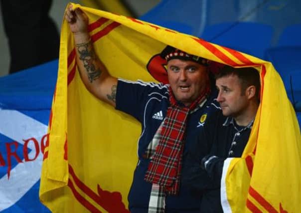 Two Scotland fans shield themselves from the rainy weather. Picture: Getty