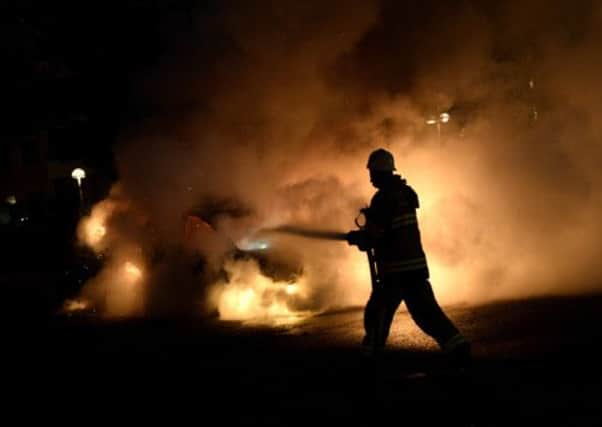 Firemen extinguish a burning car in the suburb of Kista. Picture: Jonathan Nackstrand/AFP/Getty Images