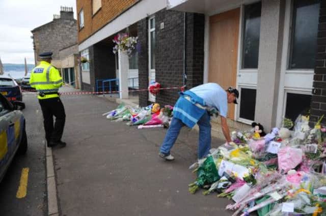 Flowers were left for the victims outside the burned out flat in Helensburgh. Picture: Robert Perry