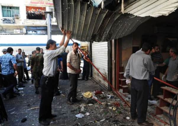 Syrians inspect a damaged shop after two explosions in central Damascus. Picture: AP