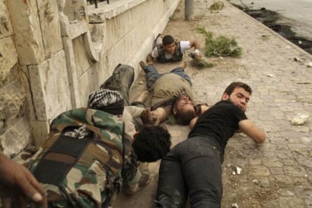 Members of the Free Syria Army's Al-Fatah brigade, duck to the ground as they pull a man who was shot by a sniper. Picture: AFP