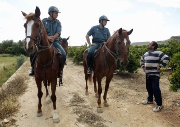 Mounted Civil Guards patrol through a field of orange trees in Liria near Valencia. Picture: Reuters