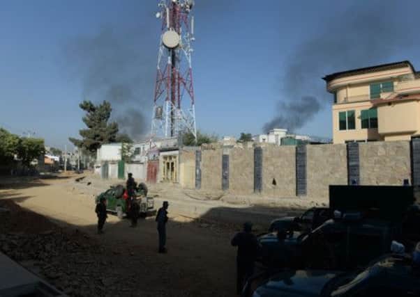 Afghan security forces stand guard as smoke rises from the entrance gate of the Presidential palace in Kabul. Picture: Getty