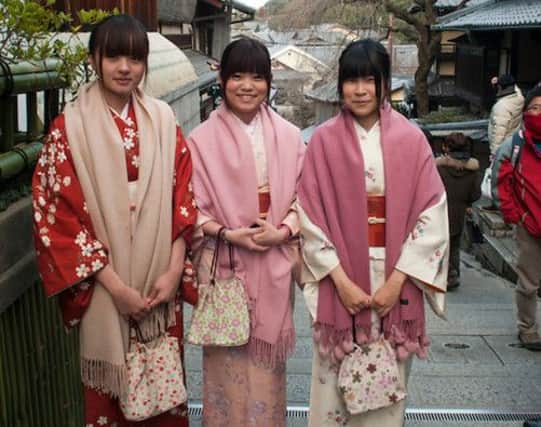 Three Japanese girls in traditional dress. Below, a whale hovers over Osaka's Dotonbori district. Pictures: Alex Hewitt