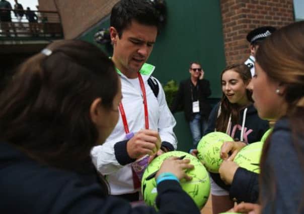 Jamie Baker signs tennis balls. Picture: Getty