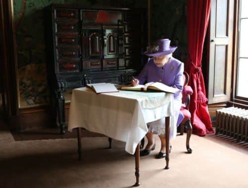 The Queen signs the guest book  during a tour of Abbotsford House. Picture: PA