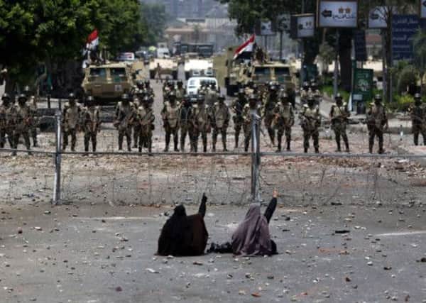 Two defiant supporters of deposed president Mohamed Morsi face armed soldiers. Picture: Getty Images