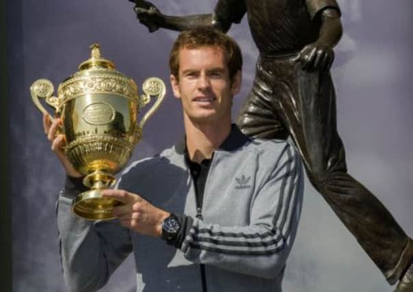 Andy Murray poses with the mens singles trophy in front of Fred Perrys statue at Wimbledon. Picture: SNS