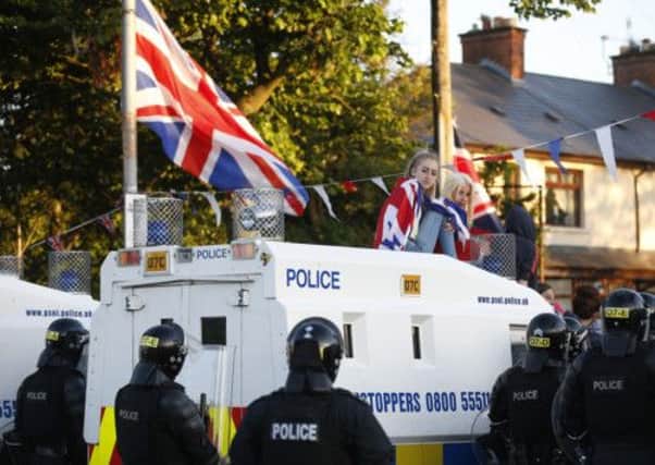 Loyalist protesters sit on top of a police armoured vehicle in North Belfast on Sunday. Picture: AP