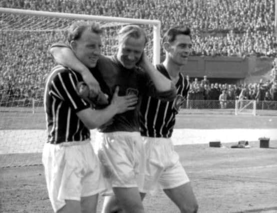 Bert Trautmann, nursing a broken neck, is helped from the field at Wembley in 1956. Picture: PA