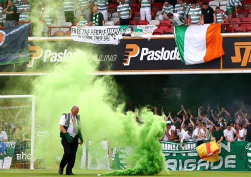 A safety officer removes a smoke bomb from the pitch during the game. Picture: Getty