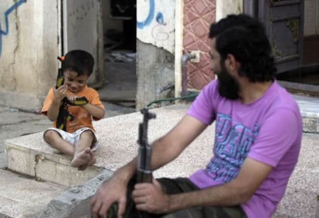 A Syrian Free Army rebel plays with a child in Deir al-Zour. The crisis is in its third year, fuelling calls for western intervention. Picture: Reuters