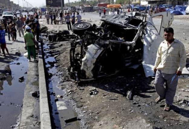 A man walks past the twisted remains of one of the car bombs in Baghdads Sadr City. Picture: AP