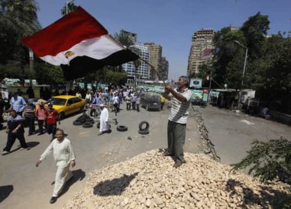 A Morsi supporter waves the flag on a barrier near Cairo University. Picture: AP