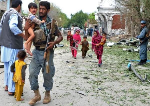 An Afghan policeman carries a child at the site of a suicide attack in Jalalabad. Picture: AFP/Getty
