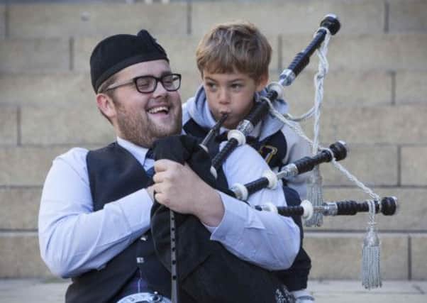 Gregor Rae from the Cowel Pipe band gives Italian visitor Alessandro Markomichelakis, six, a lesson in the drums and pipes. Picture: Chris James