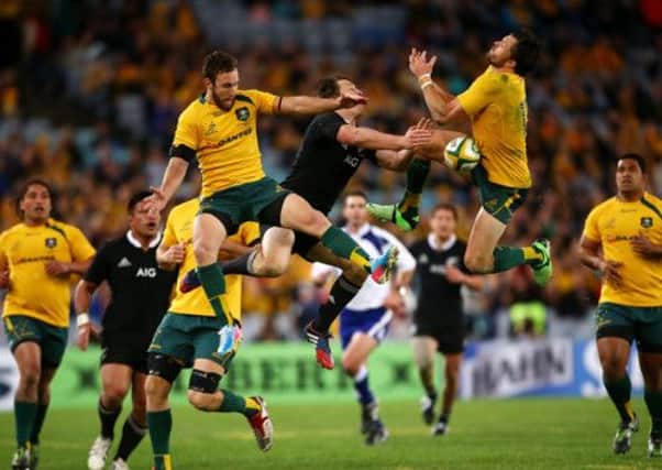Wallabies Nic White, left, and Adam Ashley Cooper jump with All Black Ben Smith. Picture: Mark Nolan/Getty