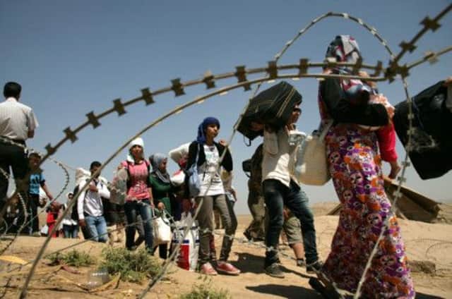 Refugees queue at the border marked by razor wire. Picture: Getty
