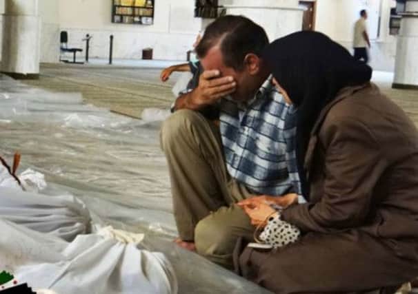A man and woman mourn over dead bodies of Syrian men killed by a chemical attack in Arbeen, Damascus. Picture: AP