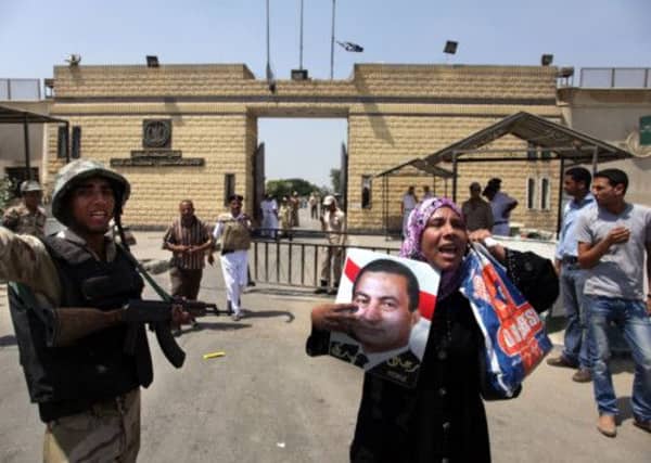 A supporter of Hosni Mubarak holds a poster of him and chants slogans in front of Torah Prison in Cairo. Picture: AP