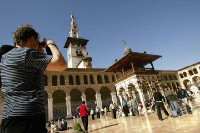 A reminder of more measured times as a tourist takes a snap outside the Umayyad Mosque. Picture: Getty Images