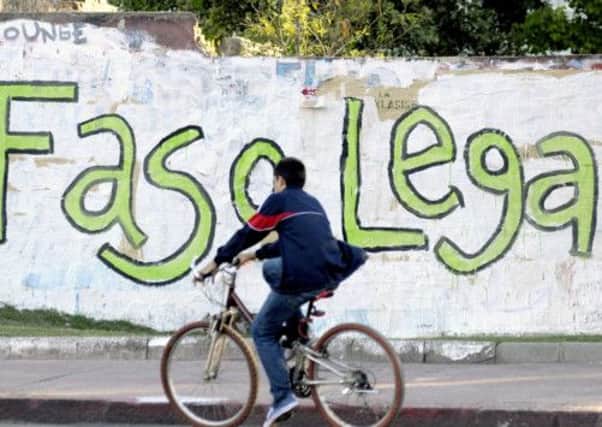 A man in Montevideo, the Uruguayan capital, rides a bicycle past a graffiti that reads in Spanish "Legal pot". Picture: AP
