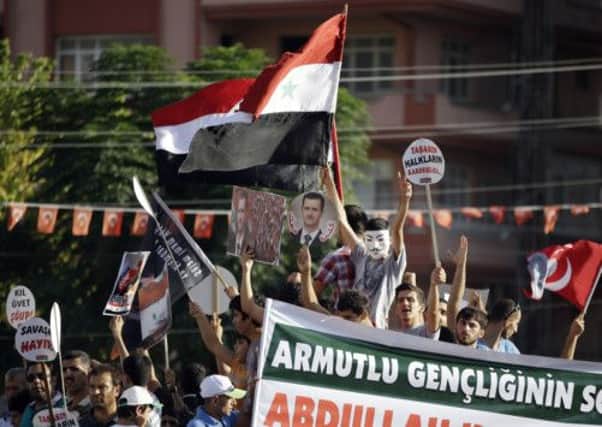 Protesters wave a Syrian flag and show posters of Syrian President Bashar Assad during a demonstration in Hatay, Turkey. Picture: AP